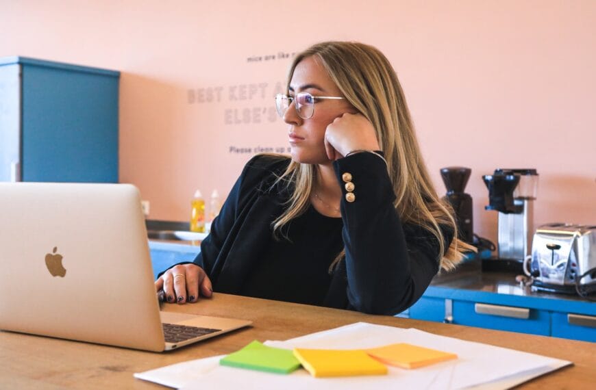 woman in black long sleeve shirt wearing black framed eyeglasses using macbook