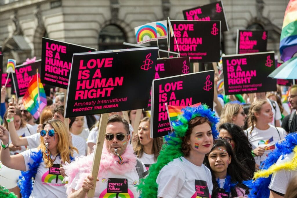Protest osób LGBT+ przeciw homofobii, Amnesty International Zdjęcie przedstawia zorganizowany przez Amnesty International protest członków społeczności LGBT+, niosących transparenty "Love is a human right".