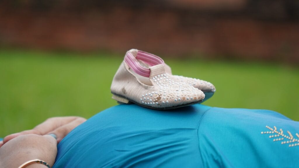 Urlop macierzyński przerwa macierzyńska - zmiana nazwy white and pink flat shoes on blue textilebiałe buciki dziecięce, brzuch kobiety w ciąży