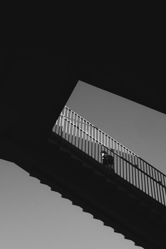 A person walks on a bridge in black and white.