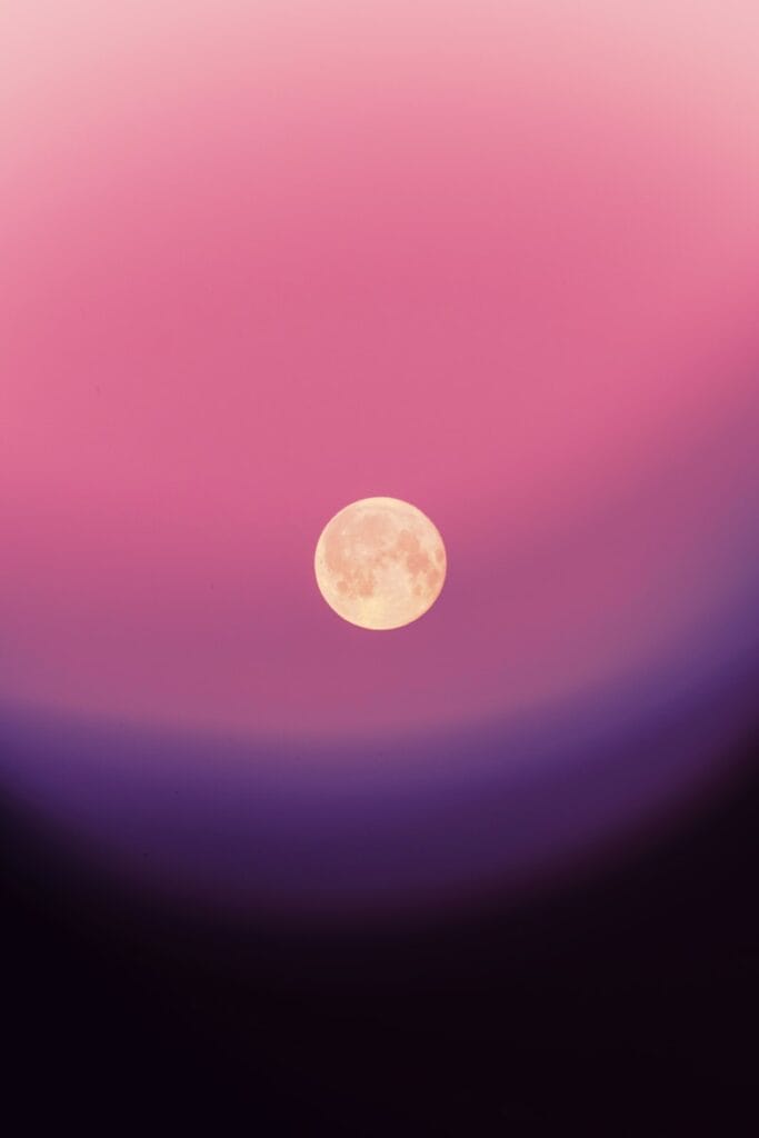 Full moon in a gradient pink and purple sky.